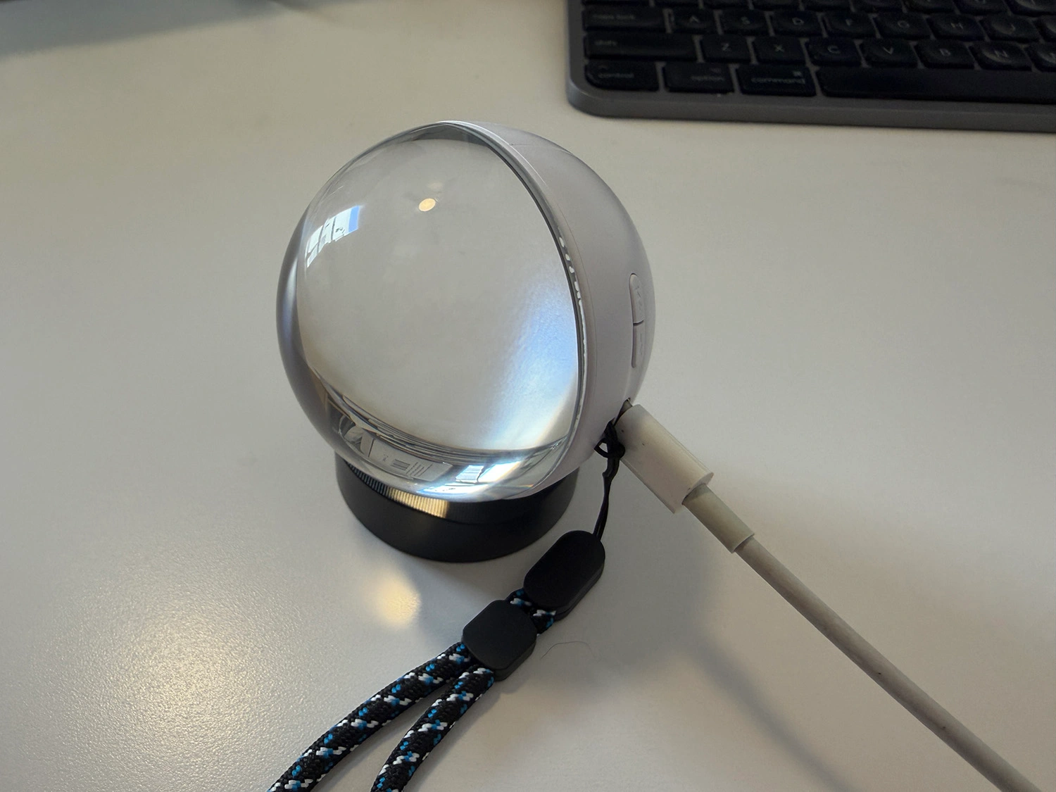 Memory Orb on its stand with a USB-C cable connected for transferring photos